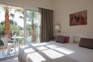 a bedroom with a bed and a balcony with a palm tree at Blue Sky Apartments in Malia
