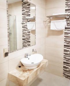 a white bathroom with a sink and a mirror at Hotel - Restauracja "SŁONECZNA" in Jarocin