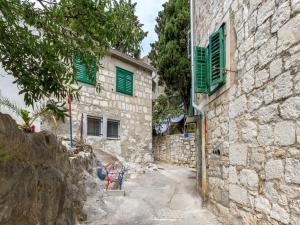 um beco com um edifício de pedra com persianas verdes em Apartment Bova em Split