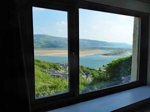a window with a view of a beach and the ocean at Bryn Melyn Apartments in Barmouth