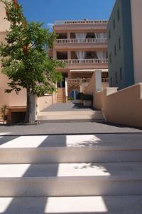 a building with a tree in the middle of a street at Agava Apartments Begic in Makarska