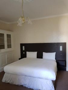 um quarto com uma grande cama branca e uma cabeceira preta em The Hebburn Great House em Hebburn-on-Tyne