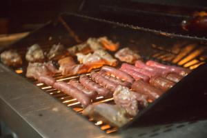 a bunch of sausages and other foods cooking on a grill at Sunset Destination Hostel in Lisbon