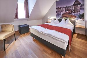 um quarto com uma cama grande e uma cadeira em Hotel Central Luzern em Lucerna