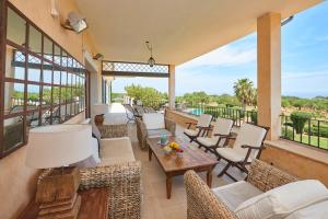 an outdoor patio with chairs and tables and windows at Villa Golf D'or in Portocolom