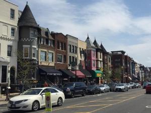 een witte auto geparkeerd in een stadsstraat met gebouwen bij Washington International Student Center in Washington