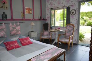 a bedroom with a bed and a table and chairs at Un Air de Campagne in Couloisy