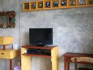 un televisor sentado en un soporte de madera con una mesa en The Picturebook Guesthouse, en Mae Sot