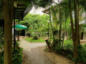 un patio con una mesa y una sombrilla verde en The Picturebook Guesthouse, en Mae Sot