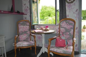 una mesa y 2 sillas en una habitación con papel pintado de color rosa en Un Air de Campagne, en Couloisy