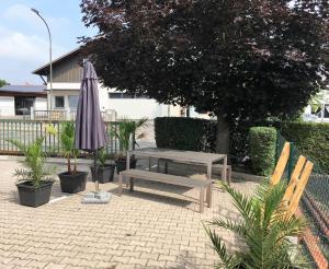 eine Terrasse mit einer Bank, einem Regenschirm und Pflanzen in der Unterkunft Urlaub in Bad Wörishofen - Wohlfühlferienwohnung in Bad Wörishofen
