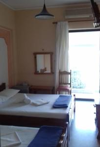 1 dormitorio con 2 camas, silla y ventana en Hotel Ionio, en Katakolon