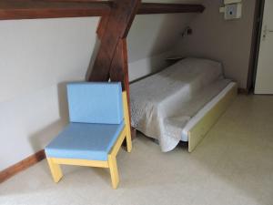 Habitación pequeña con cama y silla azul en Les Berges, en Mareuil-sur-Cher
