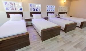 three beds in a room with wooden floors and windows at Ozbay Hotel in Pamukkale