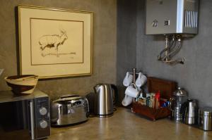 um balcão de cozinha com um micro-ondas e uma fotografia de uma cabra em Kruger River Villas - LionsGate em Marloth Park