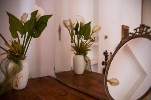 two vases with flowers on a table next to a mirror at I Giardini di Naxos in Giardini Naxos +67 photos
