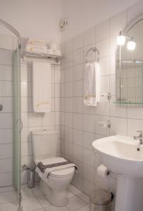 a white bathroom with a toilet and a sink at Studios Angeliki in Lassi