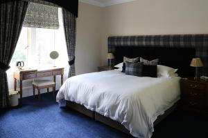 a bedroom with a bed and a desk and a window at Carnach House in Nairn