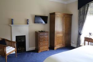a bedroom with a bed and a dresser and a fireplace at Carnach House in Nairn