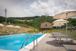 a pool with chairs and umbrellas next to a house at Agriturismo Ceriano in Modigliana