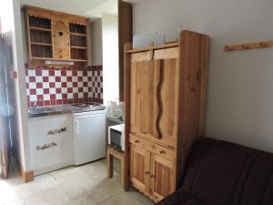 a small kitchen with a wooden cabinet and a refrigerator at Escapade in Mareuil-sur-Cher