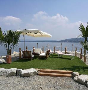 a patio with chairs and an umbrella next to the water at Katrin in Lesa