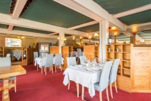 a dining room with white tables and white chairs at Logis Hotel Restaurant La Tour in Dunières