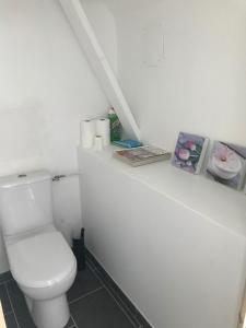 a white bathroom with a toilet and some pictures at Chez Natacha et Adrien in Regnéville-sur-Mer