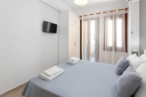 ein weißes Schlafzimmer mit einem Bett mit zwei Handtüchern darauf in der Unterkunft Elena in Symi