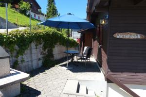 un patio con una mesa y una sombrilla azul en Chalet Wiesehockli - CharmingStay en Flumserberg