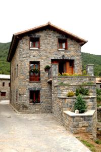 a stone house with windows and flowers on it at La Borda de Marco in Gavín