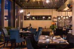 a dining room with tables and chairs and lights at Ørland Kysthotell in Brekstad