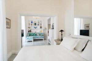 a white bedroom with a large white bed and a chair at Bellevue Syrene in Sorrento
