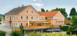 a large orange building with cars parked in a parking lot at Gasthaus Kloibhofer in Neukirchen bei Lambach