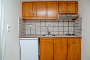 uma cozinha com armários de madeira e um frigorífico branco em Golden Bay em Agios Prokopios