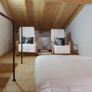 two white chairs in a room with a bed at Casinha 28 in Faro