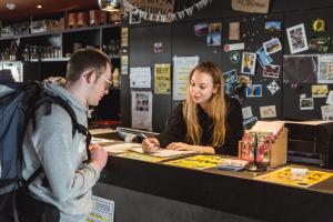 een man en een vrouw die aan een toonbank in een winkel staan bij Snuffel Youth Hostel in Brugge