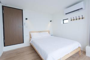 a bedroom with a white bed and white walls at No. 55 Hostel in Nangan