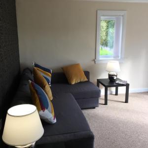 a living room with a couch and a window at West Field Apartment in Glasgow