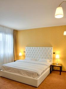 een groot wit bed in een kamer met 2 lampen bij Trattoria Al Gallo in Bran