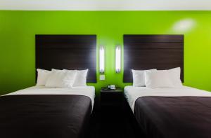 two beds in a room with a green wall at Palacio Royale Inn Boutique Katy in Katy