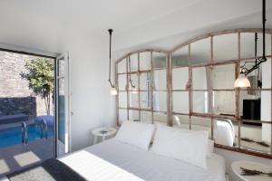 una camera da letto con un letto bianco e una grande finestra di Erosantorini Estate a Firà Altre 37 foto