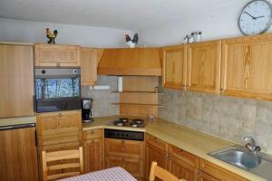a kitchen with wooden cabinets and a clock on the wall at Haus Alvier - CharmingStay in Flumserberg