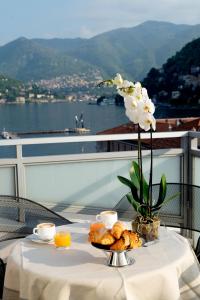a table with a plate of food and a vase of flowers at Hotel Barchetta Excelsior in Como