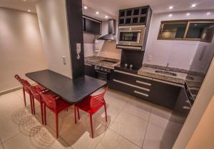 a kitchen with a black table and red chairs at Luxor Paulo Miranda By Penareia in João Pessoa