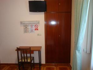 Habitación con mesa, silla y armario. en Hostal Zamora, en Madrid