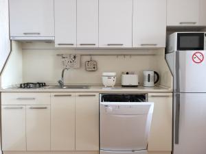 a small kitchen with white cabinets and a refrigerator at Apartments in the Center of Batumi in Batumi