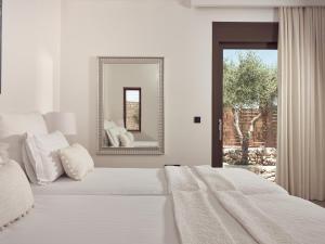 a white bedroom with a bed and a mirror at PanoPlagia Villa in Agios Nikolaos