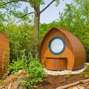 a small wooden building with a round window on it at Glamping Resort Biosphäre Bliesgau in Kleinblittersdorf +7 photos