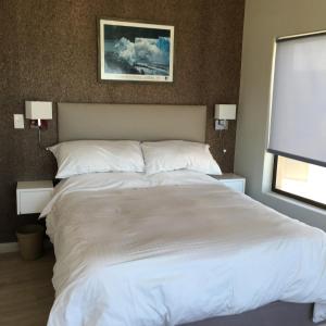 a large white bed in a bedroom with two lamps at Ocean view, Swakopmund, 3-bedroomed apartment in Swakopmund